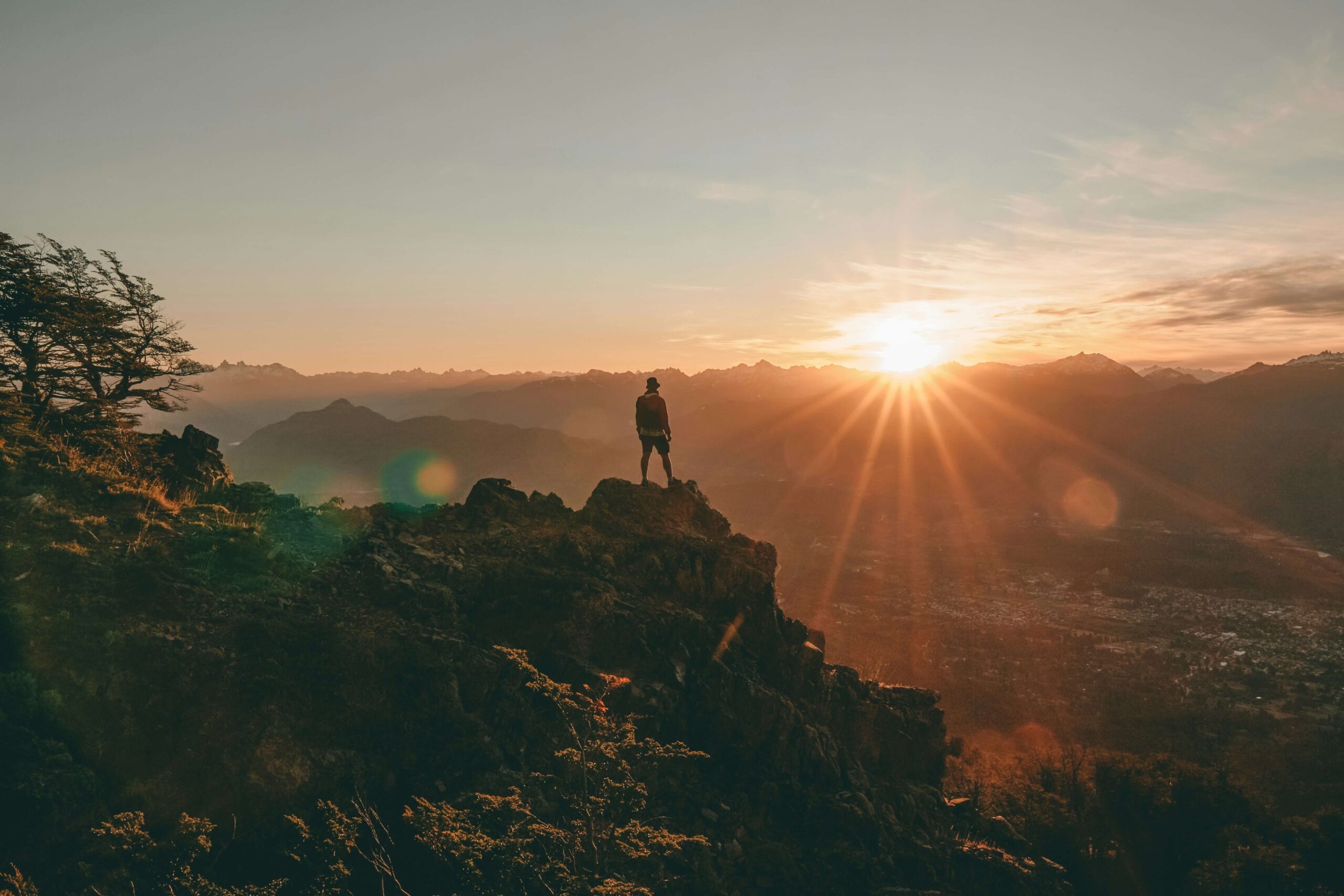 Mann auf Berg sieht in den Sonnenuntergang